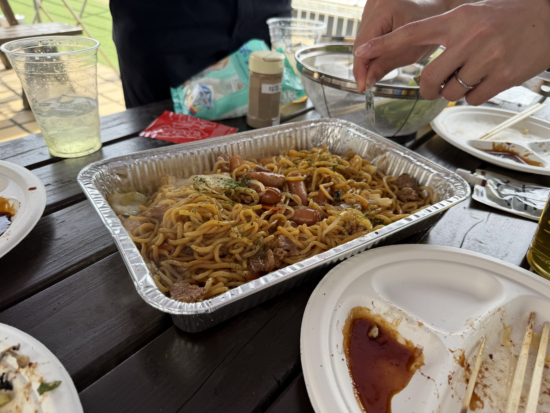 Yakisoba served in a foil tray on an outdoor wooden table.