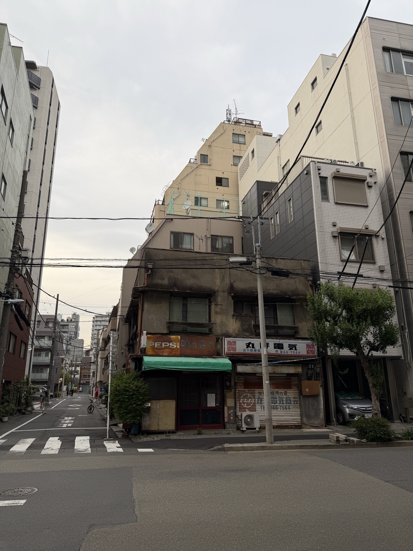 Old Tokyo buildings, overhead wires, and a cloudy morning sky.